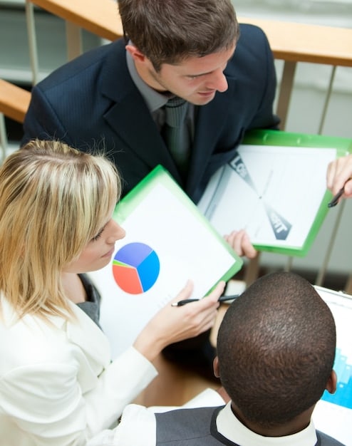 A group of people in a business meeting, some pointing at a chart.