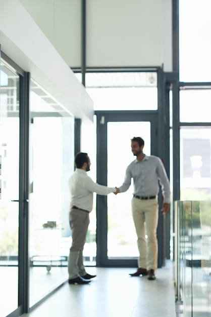 Two business partners are shaking hands firmly inside a modern office, symbolizing the agreement being made. A lawyer stands nearby, holding documents, to signify the legal aspect of the co-founder agreement. The scene is brightly lit with natural sunlight.