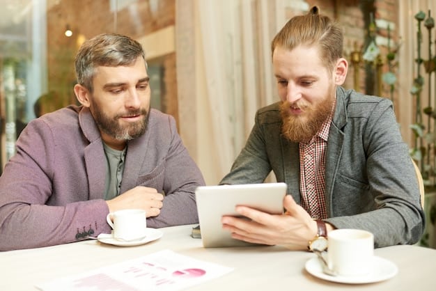 Two co-founders sitting across from each other at a table, one holding a tablet with performance data displayed, both engaged in a thoughtful conversation.