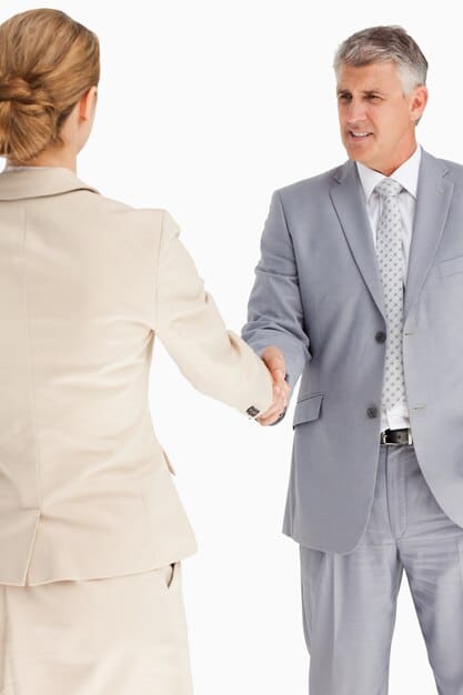 A handshake between two individuals in a professional setting, symbolizing a strong partnership and trust, potentially after a successful angel investment deal. Background shows a blurred modern office.