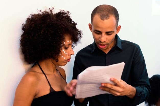 A close-up of two diverse individuals, one male and one female, intently reviewing documents spread across a conference table, with legal pads and pens, suggesting detailed work on contracts or agreements. The atmosphere is professional and focused.
