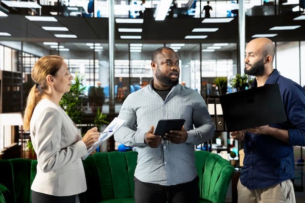 A diverse group of business professionals in a modern office working collaboratively, with some reviewing documents and others engaged in discussion, representing effective team collaboration and compliance efforts within an organization.