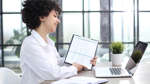 A person reviewing documents related to insurance in a well-lit office, with a laptop displaying cybersecurity data in the background, indicating cyber insurance review, connecting to Insurance Compliance: Essential Coverage to Protect Your Startup from Liability.